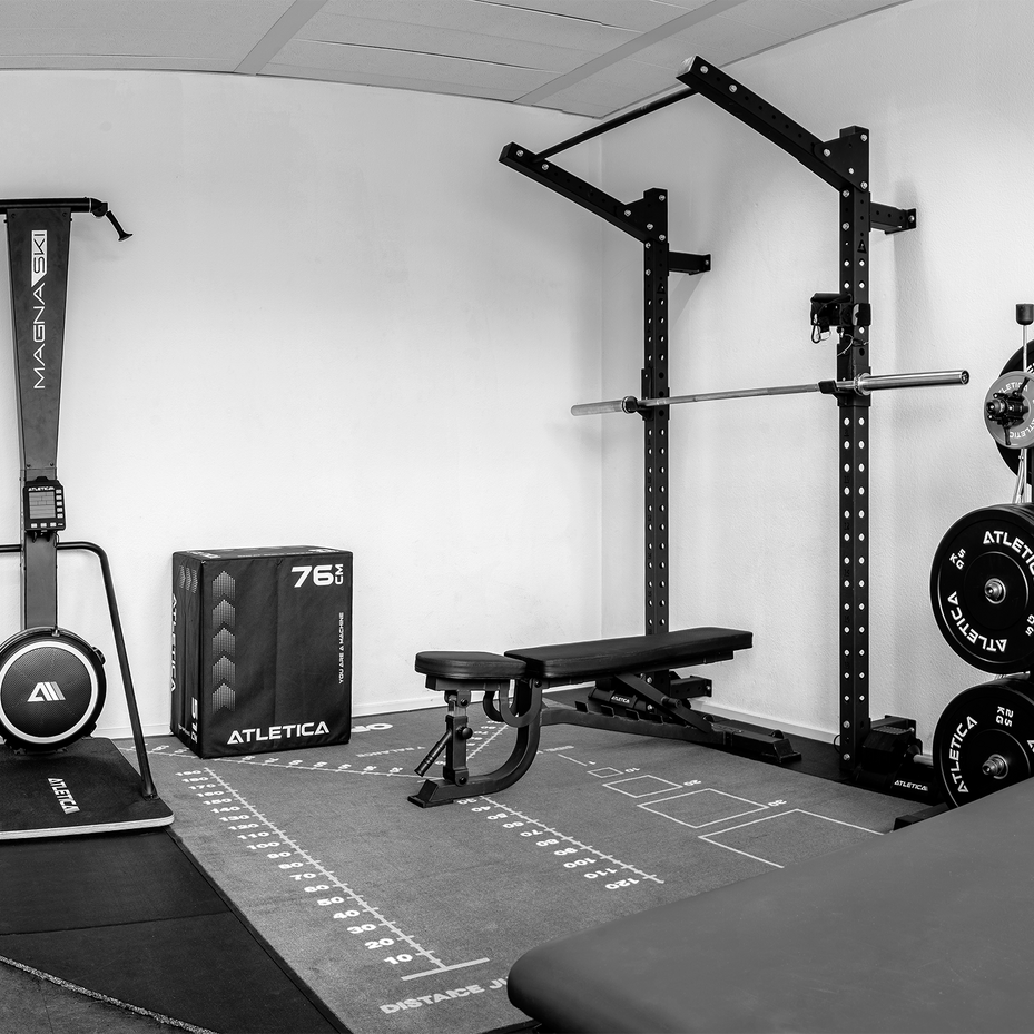 Trainingsraum mit Hantelbank, Kraftstation, Gewichtsscheiben und Fitnessgeräten.
